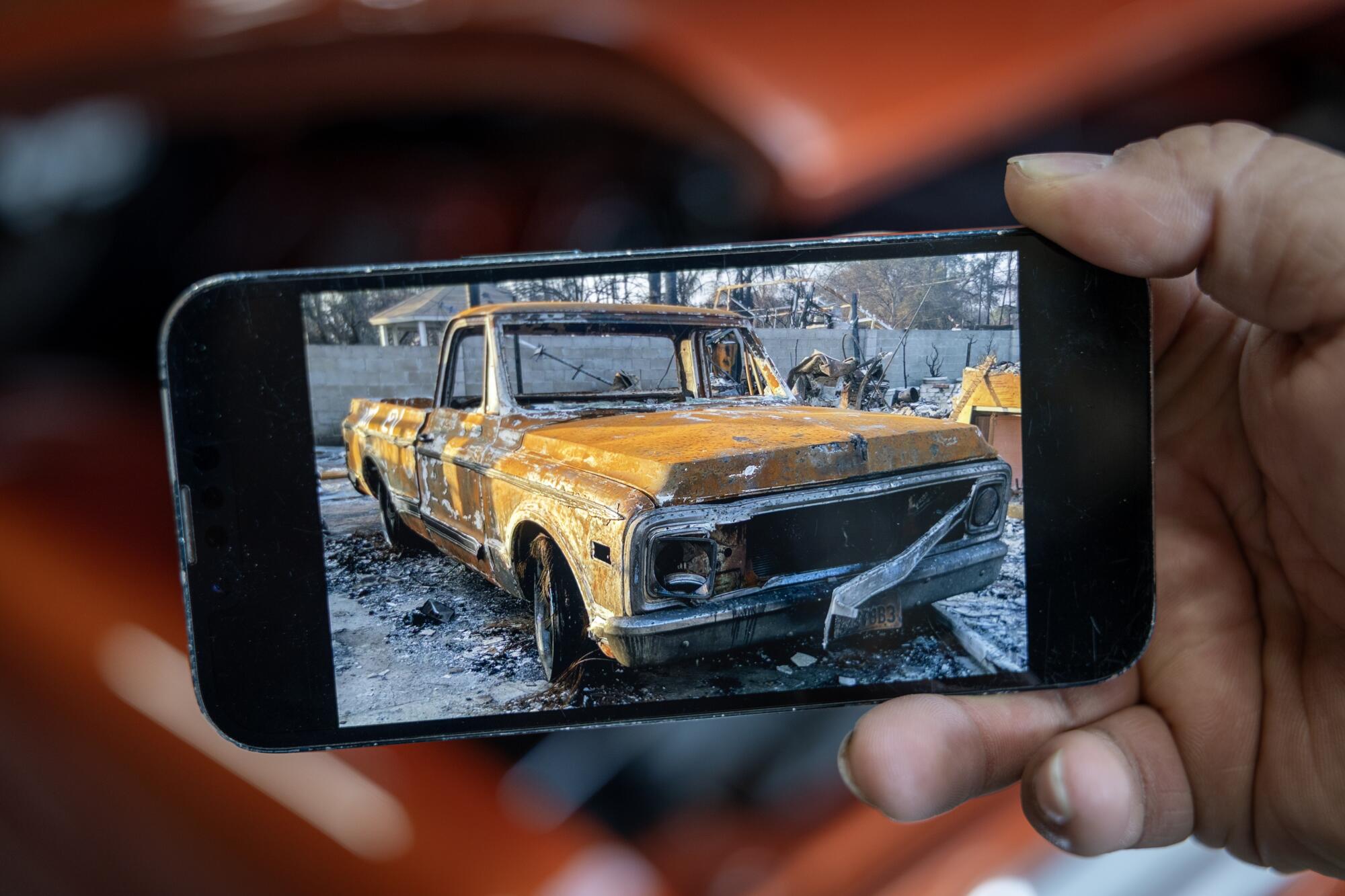 A phone with a photo of the burned-out 1972 Chevy C10 short bed being shown.