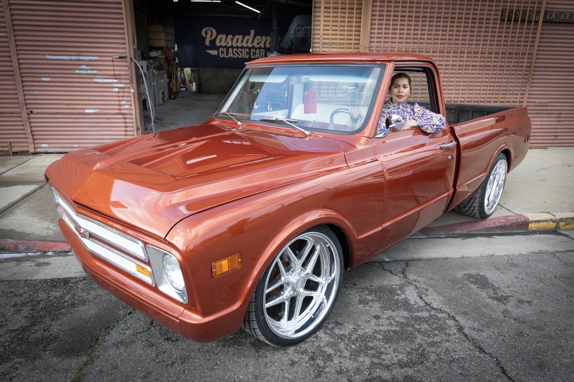 A woman sits in her restored truck for a portrait.