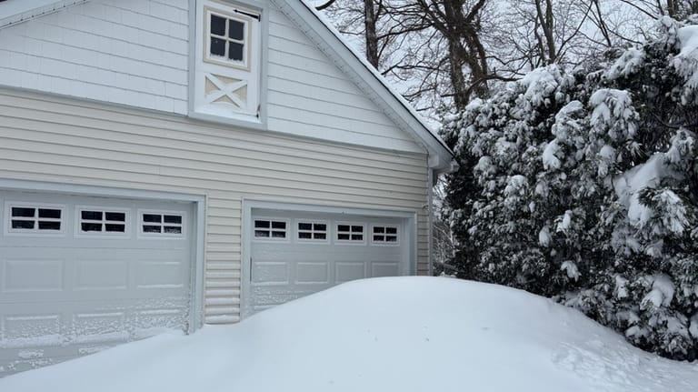 A large snow drift outside a garage in a residential...