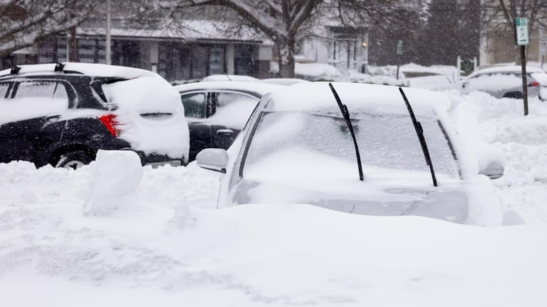 A car buried in snow in a parking lot in...