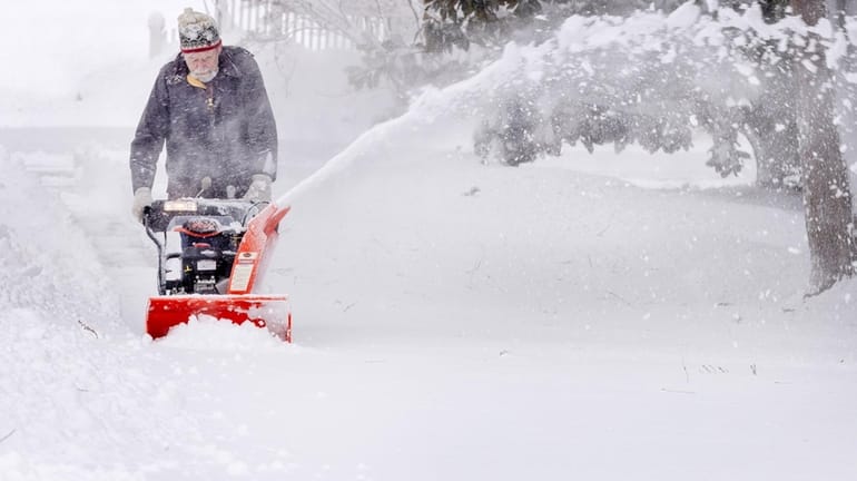 Huntington Village resident Dick Kelley clears a path on the...