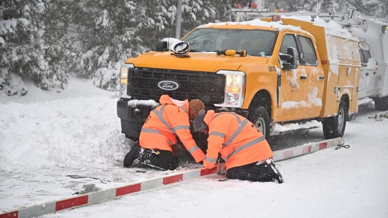 Crews fix an LIRR crossing gate after it blew off in...