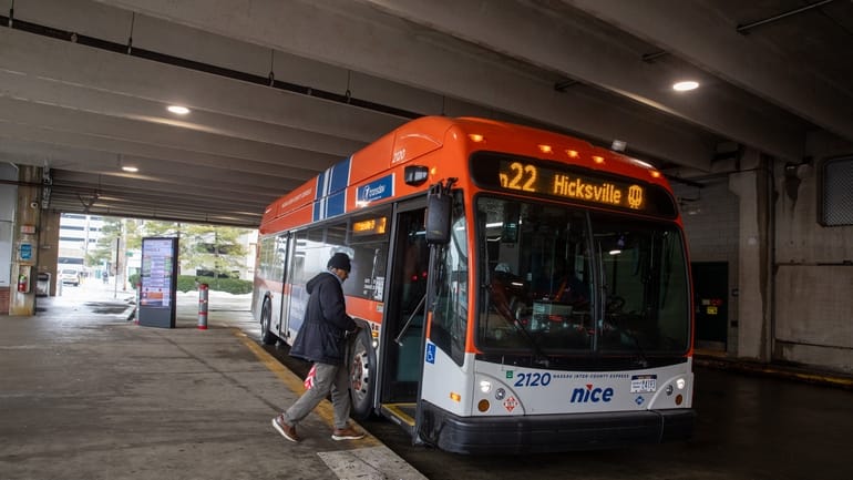 A rider boards a NICE bus at a stop in Mineola...