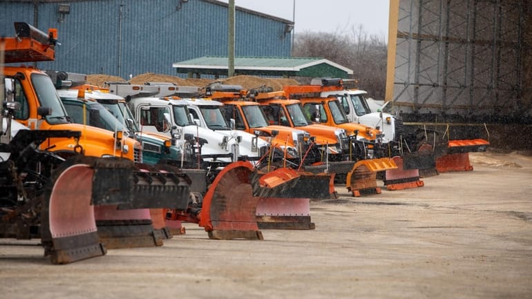 Snow plows filled with salt are lined up in the...