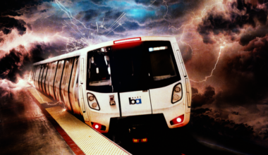 A BART train emerges from dark storm clouds with lightning illuminating the turbulent sky above the platform.
