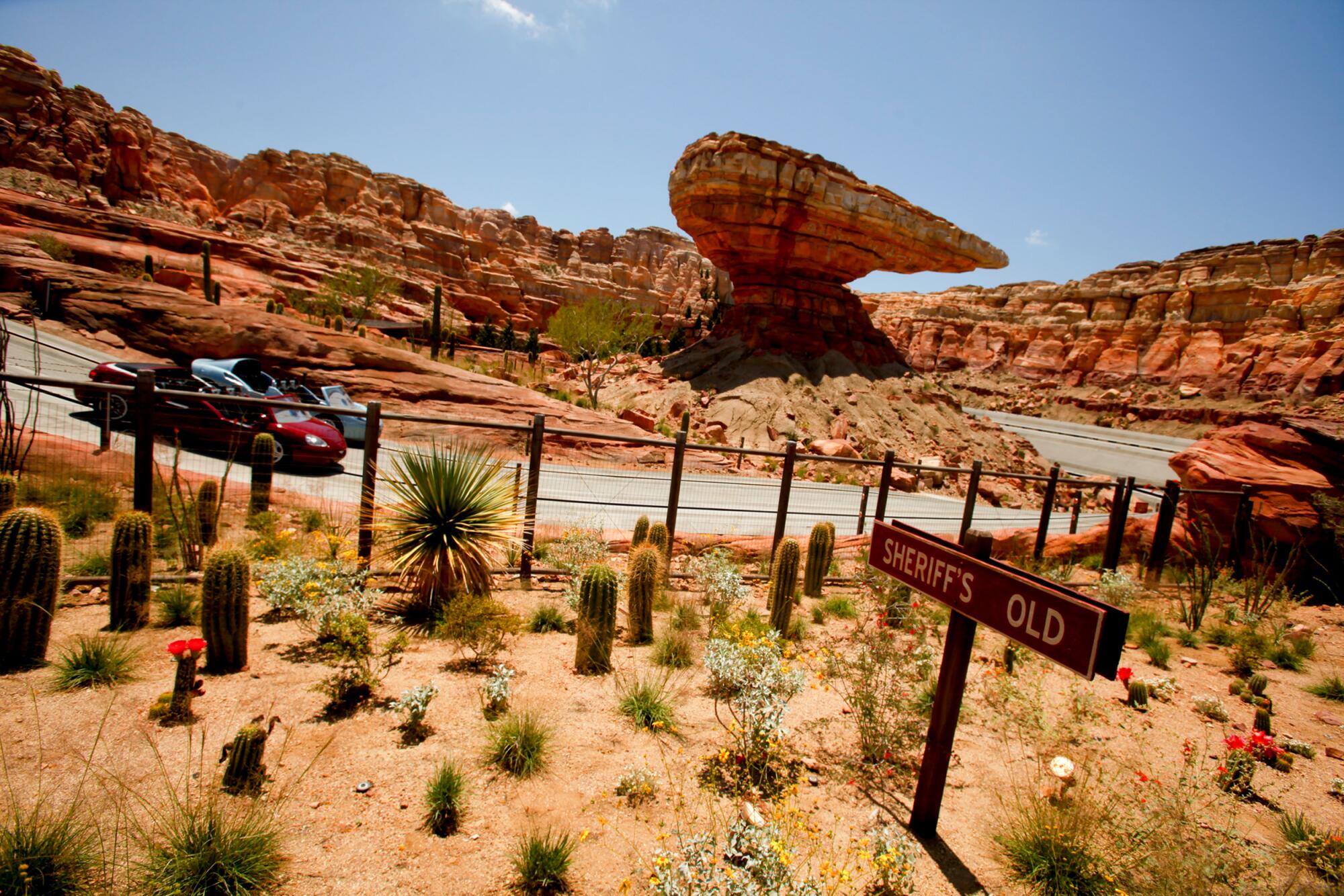 Theme park rock work designed to look like the Southwest with two racing cars in the foreground.