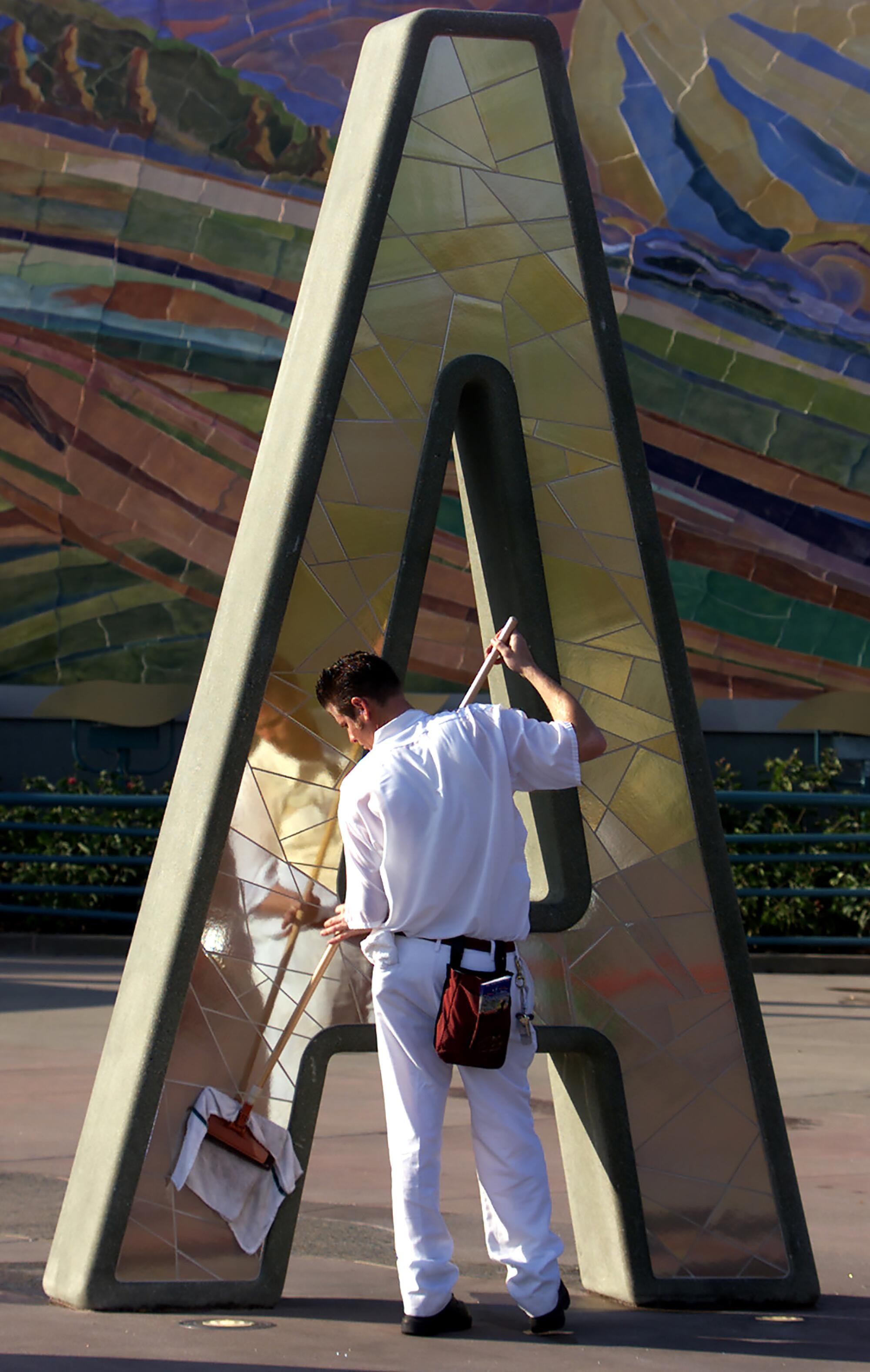 A Disney cast member polishing a giant letter. 