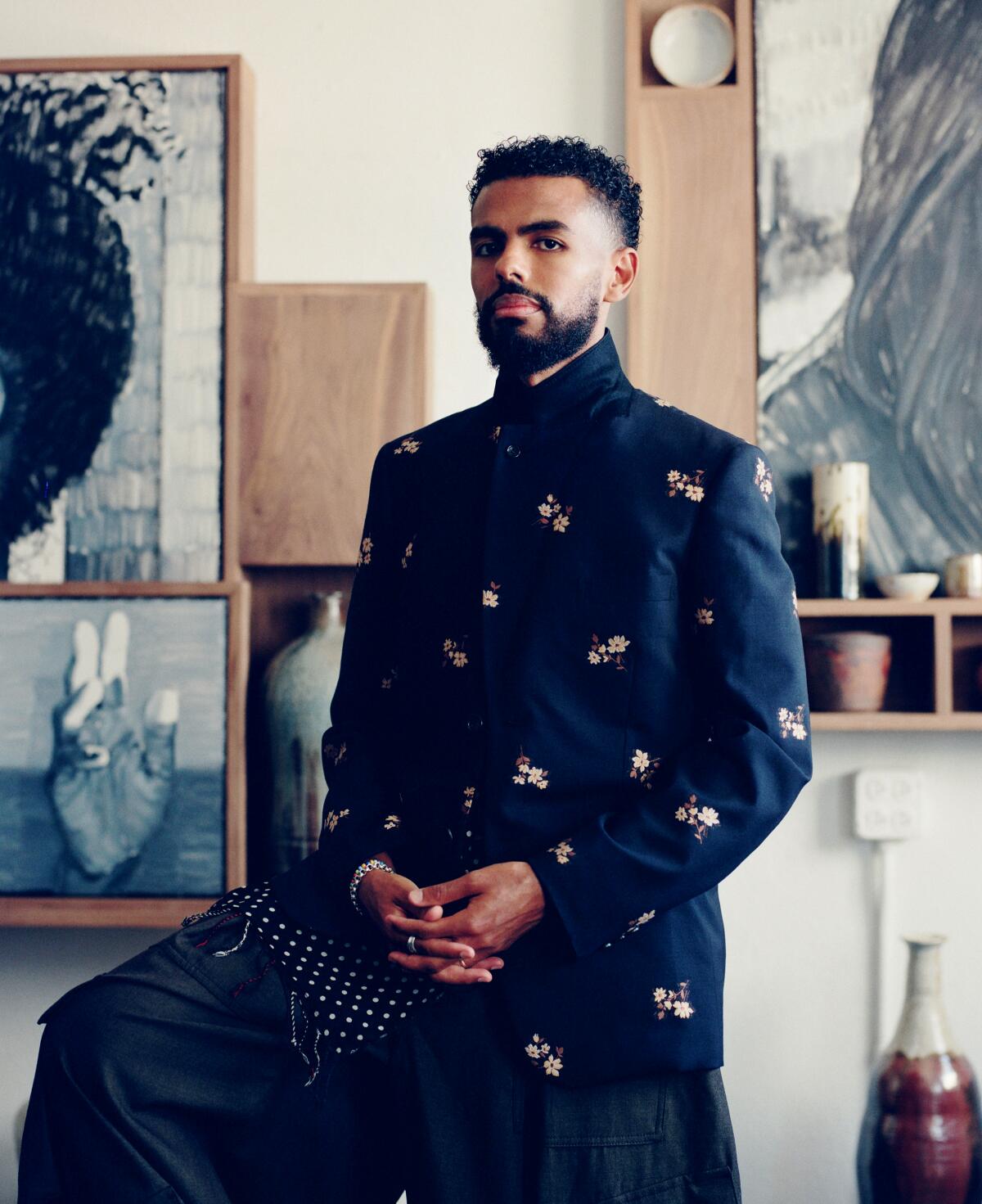 A man stands in front of a piece of art.