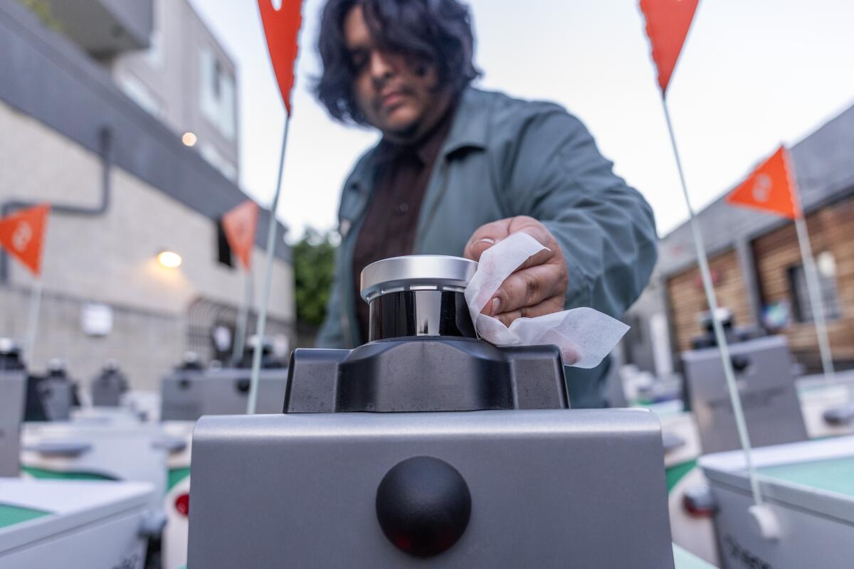 Serve Robotics field agent Tony Perez wipes the lidar lens on a delivery robot as they are readied for service.
