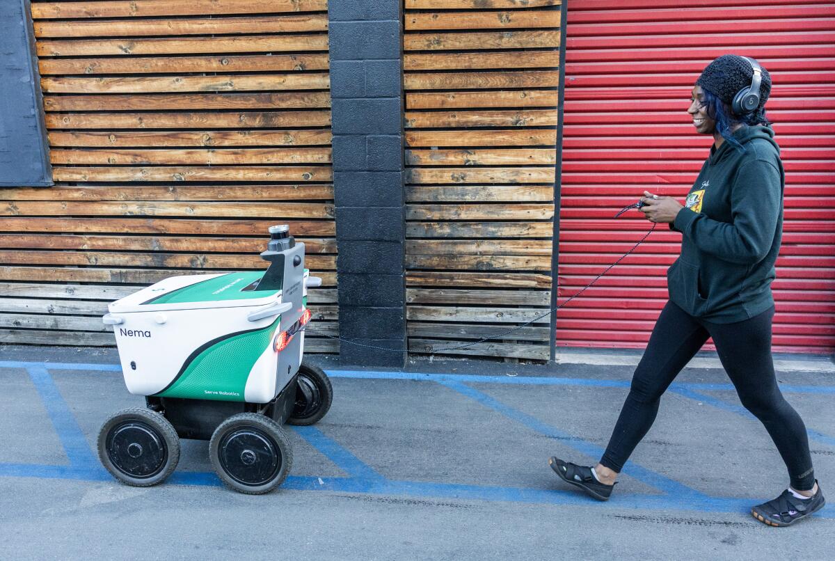 Serve Robotics technician Tia Kye checks a robot that was brought in with reported wheel problems.