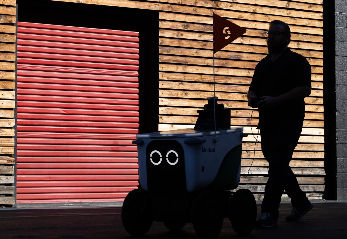 A Serve Robotics supervisor drives a robot to a holding area.