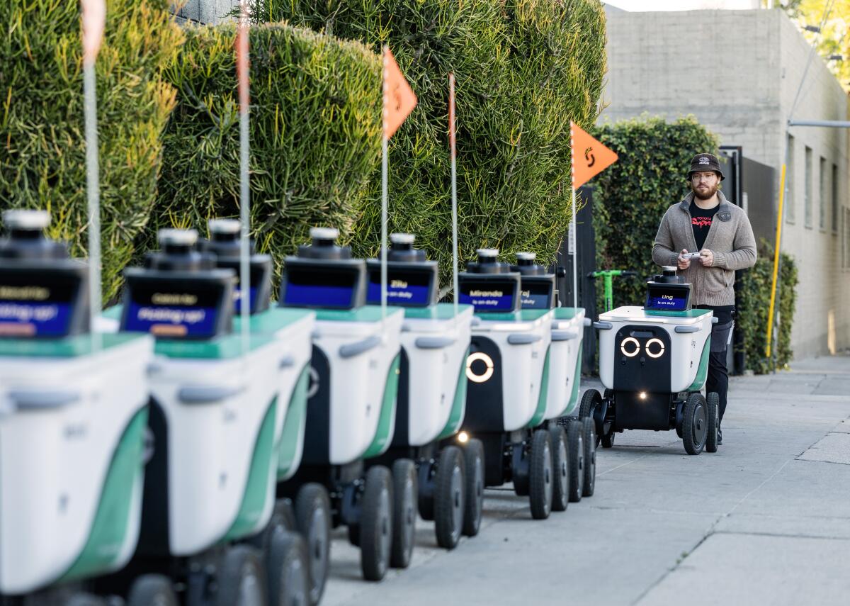 Robot wrangler Charlie Snodgrass gets the robots on the sidewalk outside Serve Robotics' depot in Los Angeles.