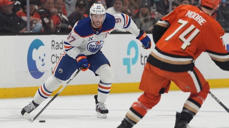 Edmonton Oilers center Connor McDavid, left, looks to pass as...