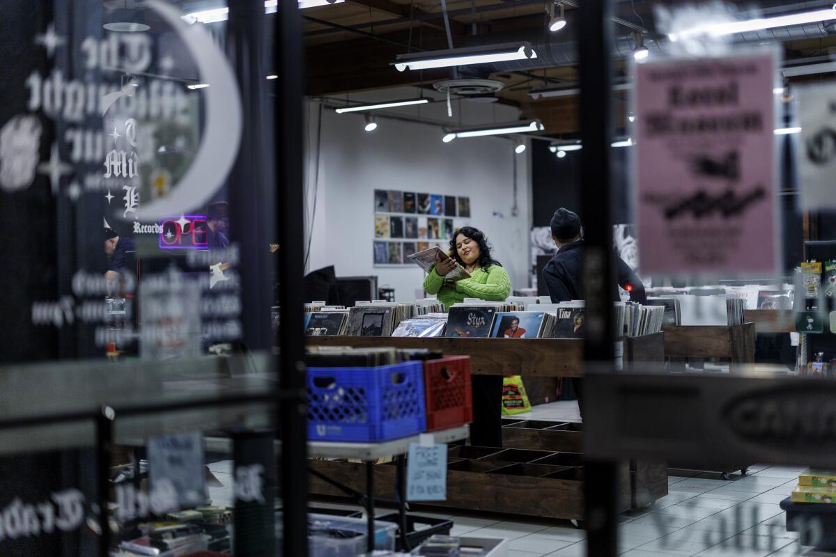A woman browses through vinyl albums at a record store 