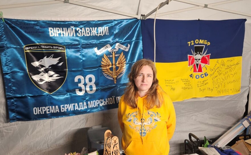 Tetiana Markova of San Jose poses with the flags of two Ukrainian brigades, signed by soldiers who benefitted from her donations.