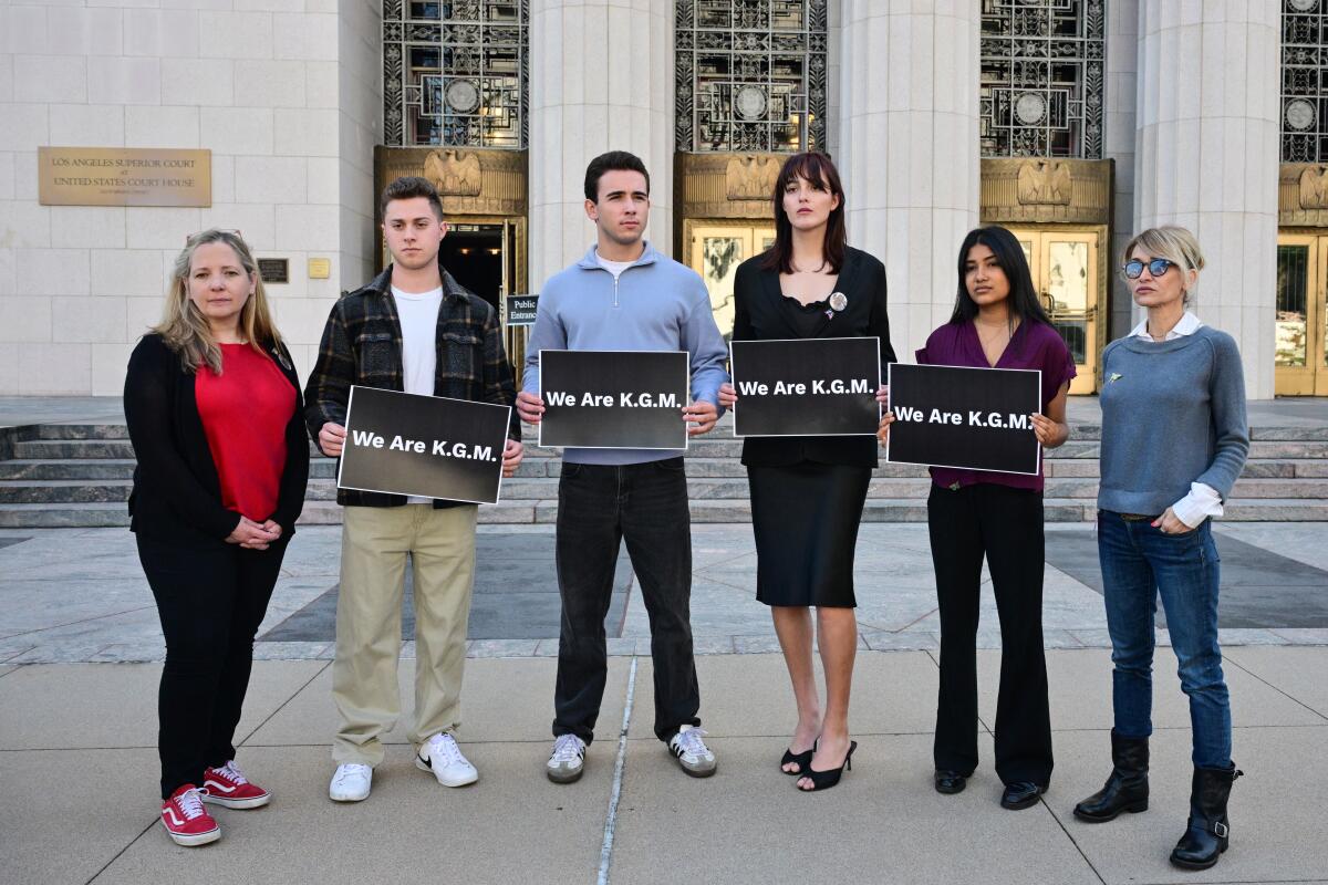Supporters of "K.G.M." pose with signs outside Los Angeles Superior Court.