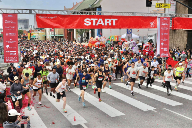 A large group of runners at the starting line of a race, under a banner that reads "Start." 