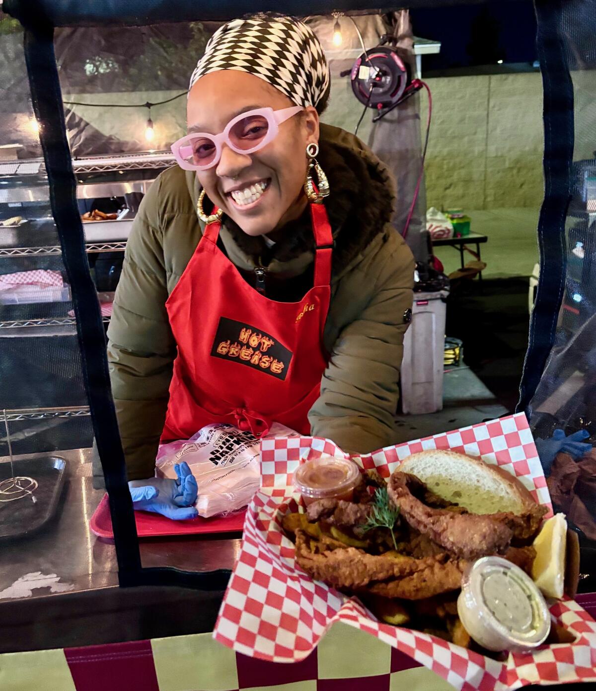 Asha Starks hands a customer an OG plate, with crispy snapper fillets, fries and bread.