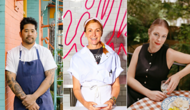 Three people are pictured: a tattooed man in a white shirt and blue apron, a smiling woman in a white chef coat, and a woman in a black dress sitting at a table with food and drink.