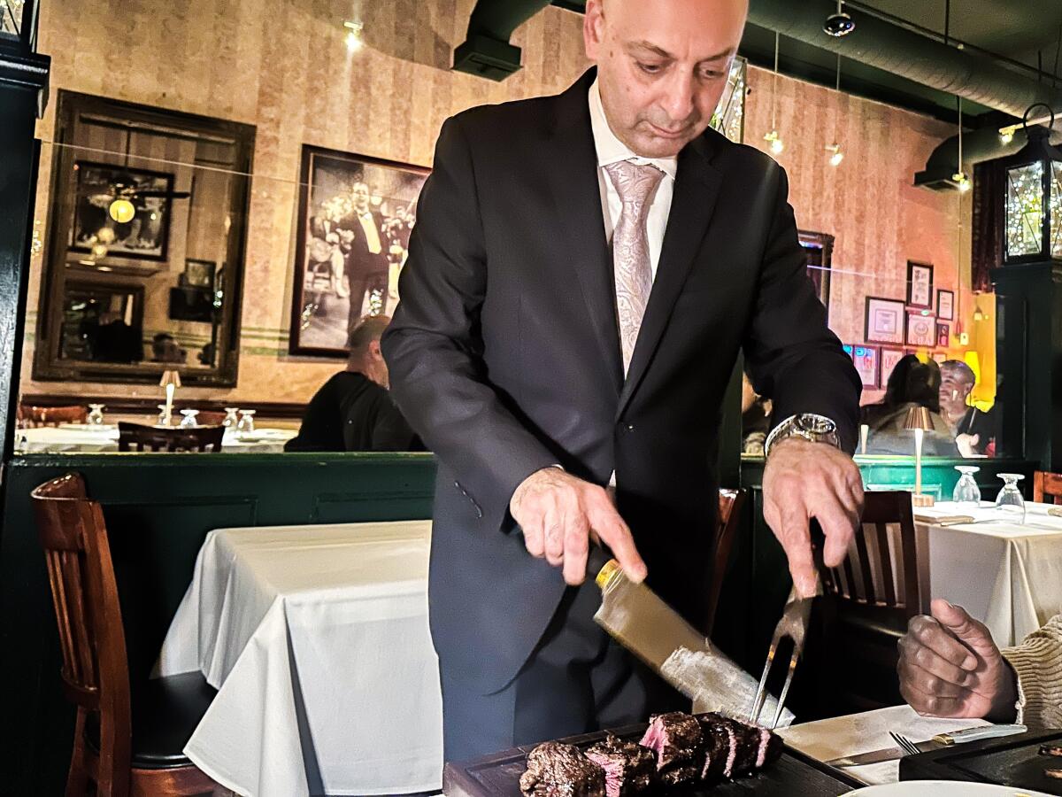 Co-owner and sommelier Max Bozoghlian carves steak tableside at Carlitos Gardel.