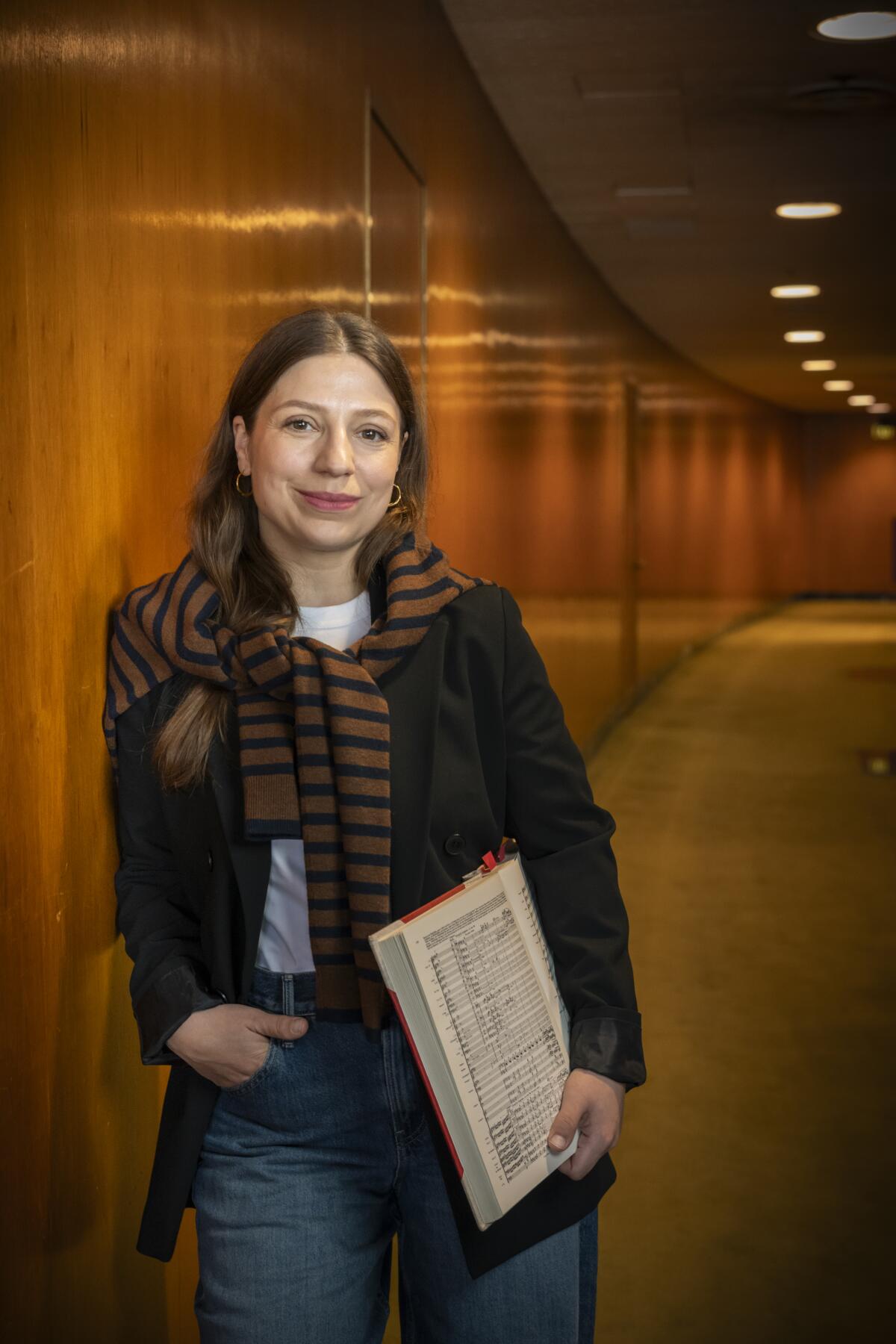 A woman leans against a wall.