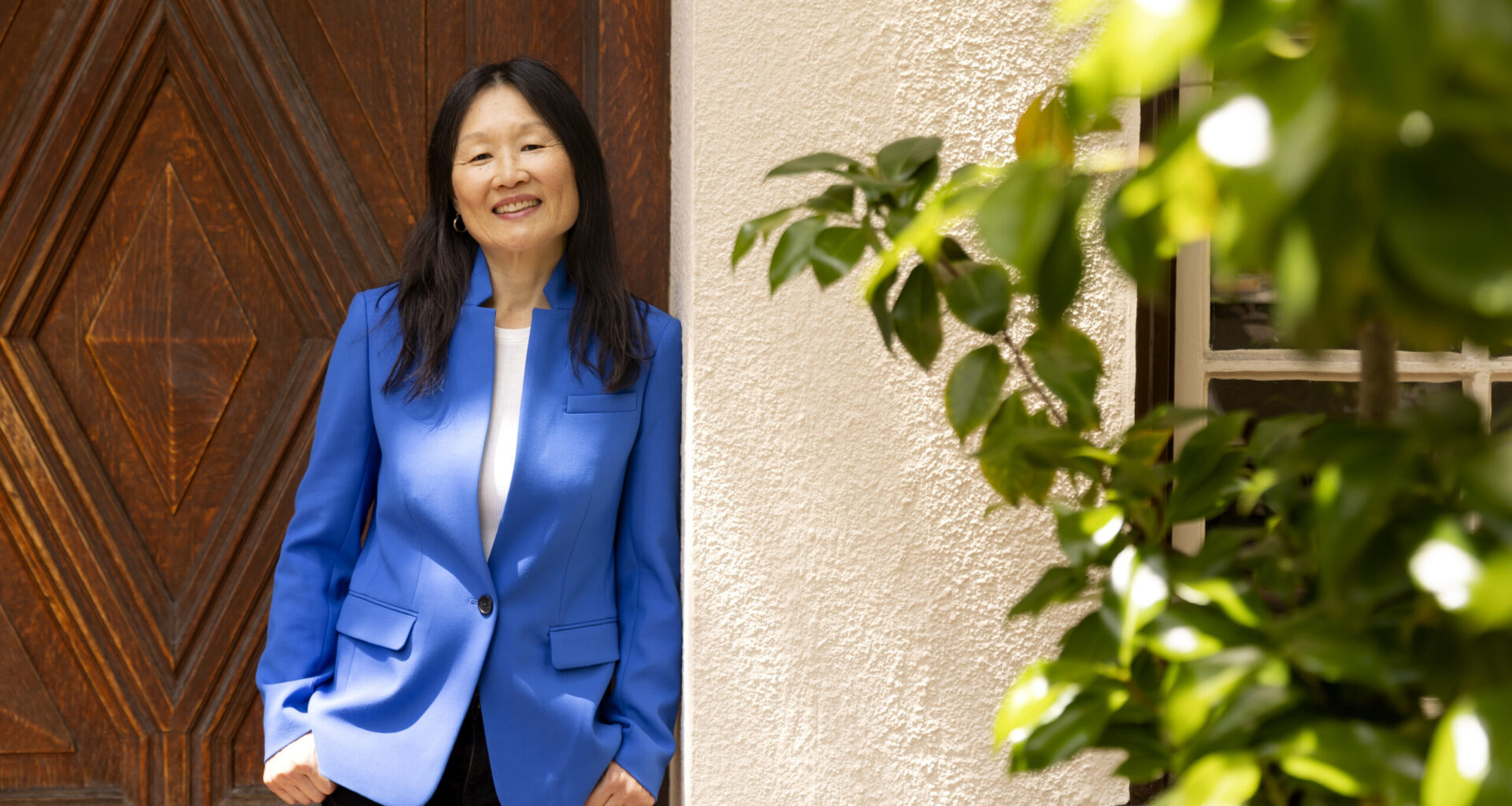 sarah song in a blue jacket leaning against a building