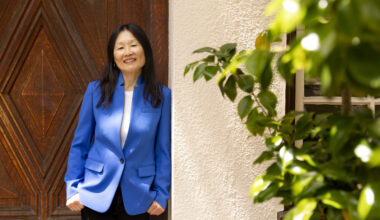 sarah song in a blue jacket leaning against a building
