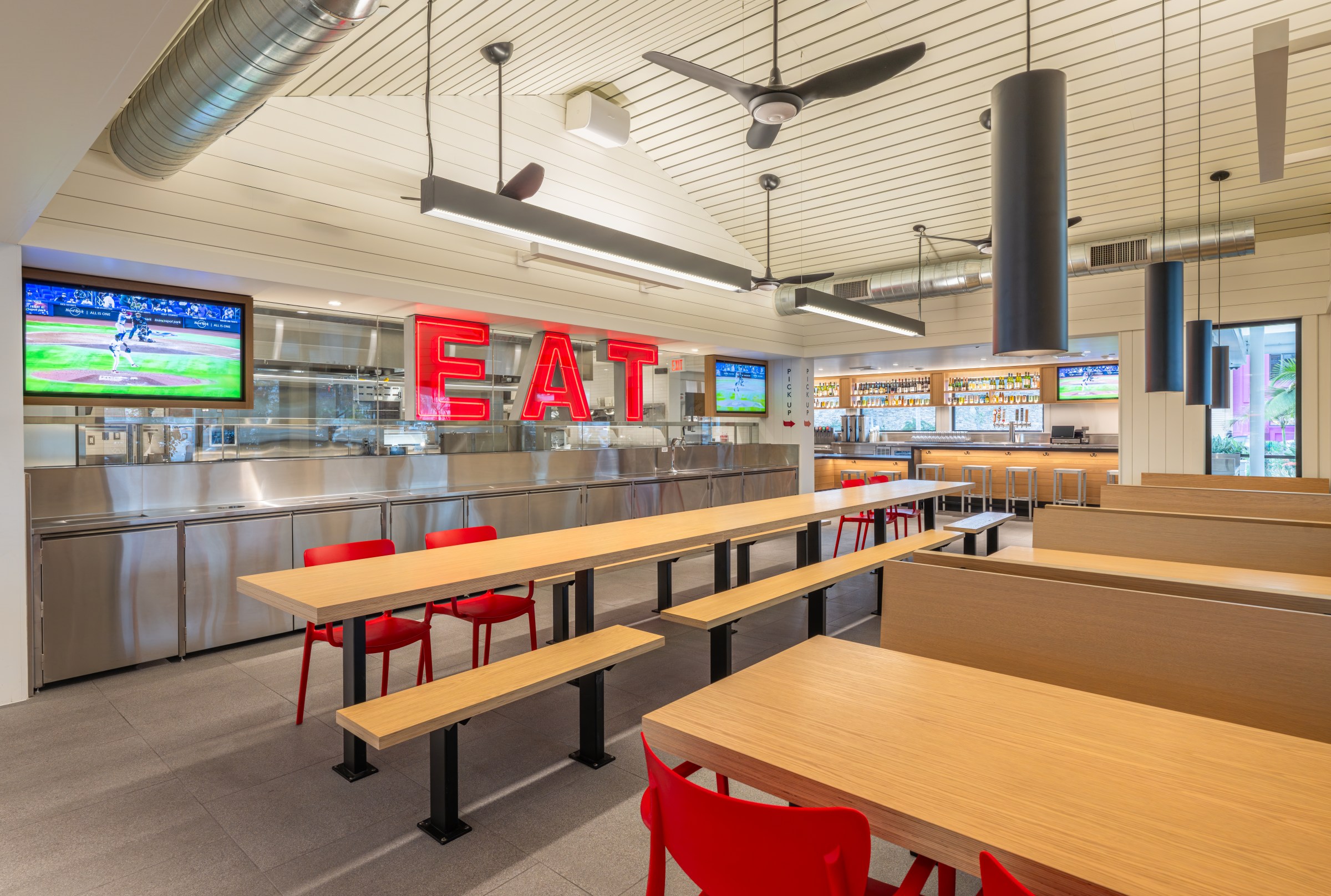 Interior dining room at Gott’s with wood tables at a red “EAT” sign.