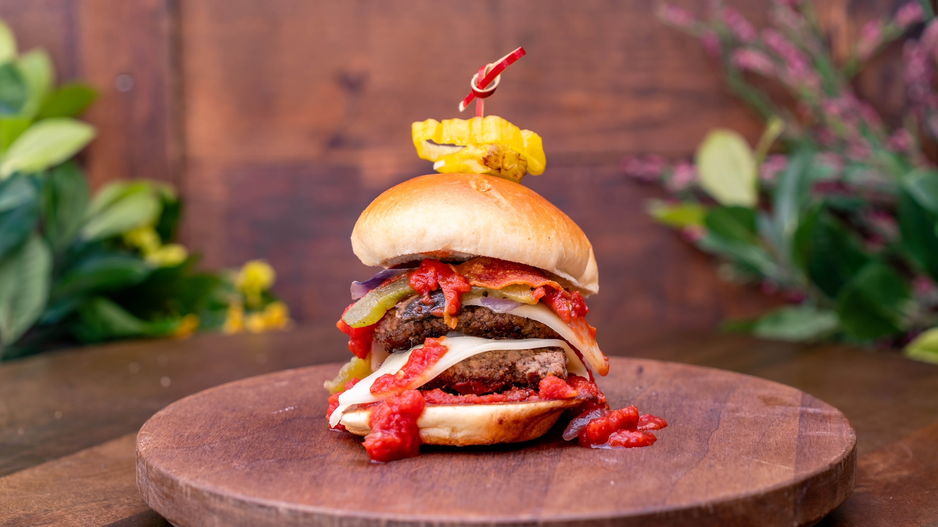 Pizza Slider: Slider beef patty with mozzarella cheese, fried pepperoni, bell peppers and onions, sautéed mushrooms, and marinara sauce served on a brioche bun and garnished with pepperoncini