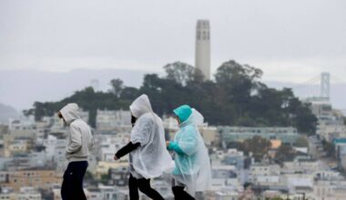 Visitors take in city views at Hyde and Lombard streets as rain begins to soak the Bay Area, in ...