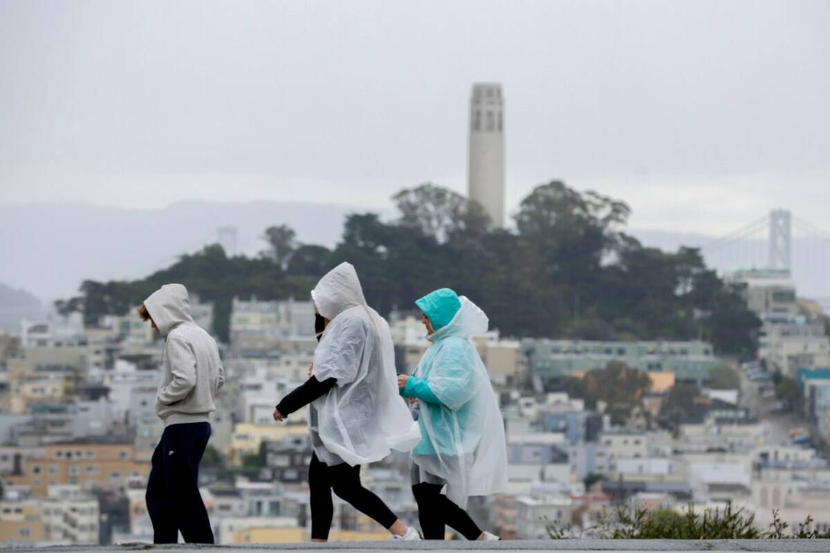 Visitors take in city views at Hyde and Lombard streets as rain begins to soak the Bay Area, in ...