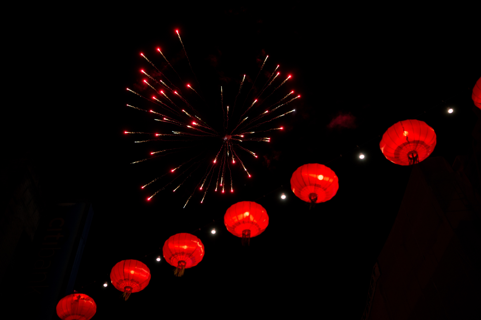 Fireworks are seen above a string of red lanterns.