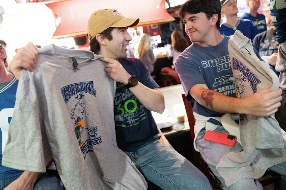 Ryan Kinerk, left, and Elijah Tan hold up recently purchased merchandise at Danny Coyle's in San Francisco before the Super Bowl. (Minh Connors/For the S.F. Chronicle)
