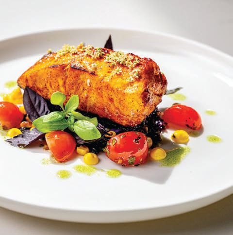 Sea bass, with achiote marinade, forbidden black rice, charred sweet corn, wilted spinach and Toy Box cherry tomatoes chimichurri PHOTO COURTESY OF BRAND