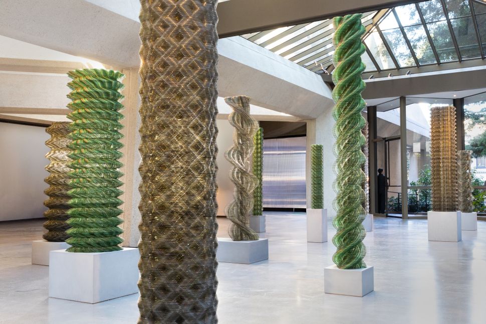 Installation view of Tara Donovan’s twisting column sculptures made of stacked translucent discs inside a light-filled modernist interior.