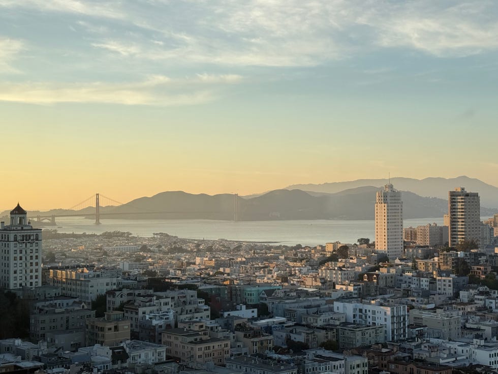 Cityscape featuring bay and bridge at sunset.