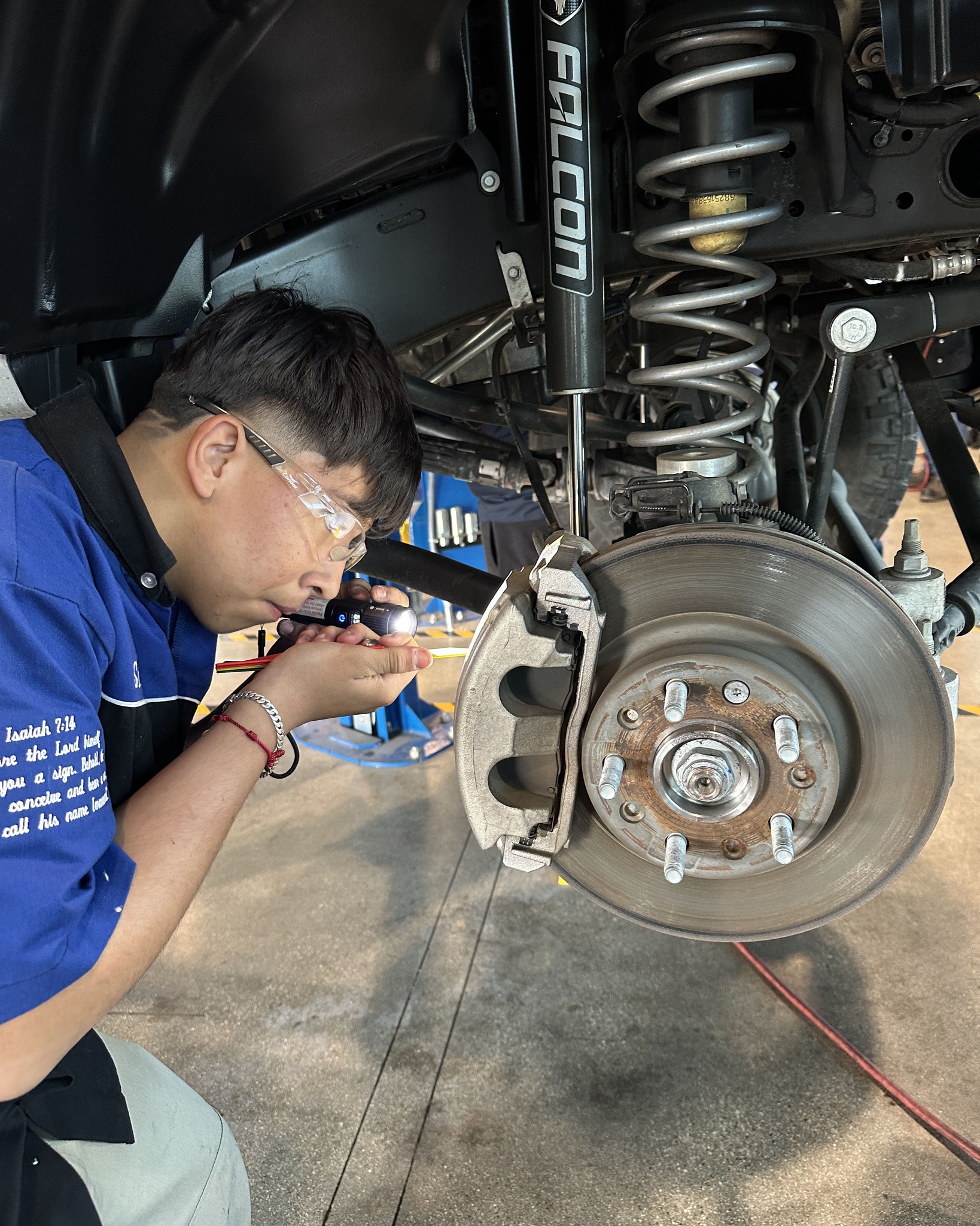 A Valley High School automotive student works beneath a vehicle during the Auto Academy Saturday Community Garage Service Clinic at the school’s CTE automotive facility.