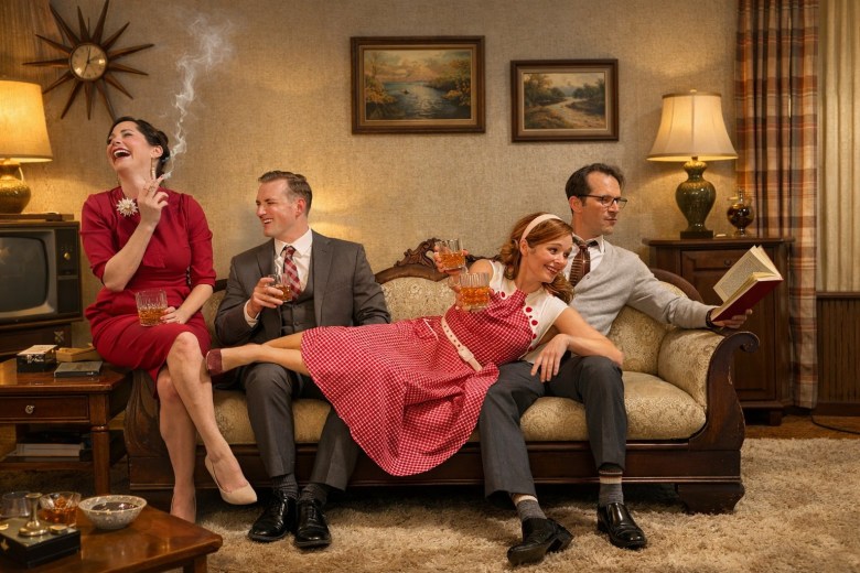 Two couples recline on a touch, drinking and smoking