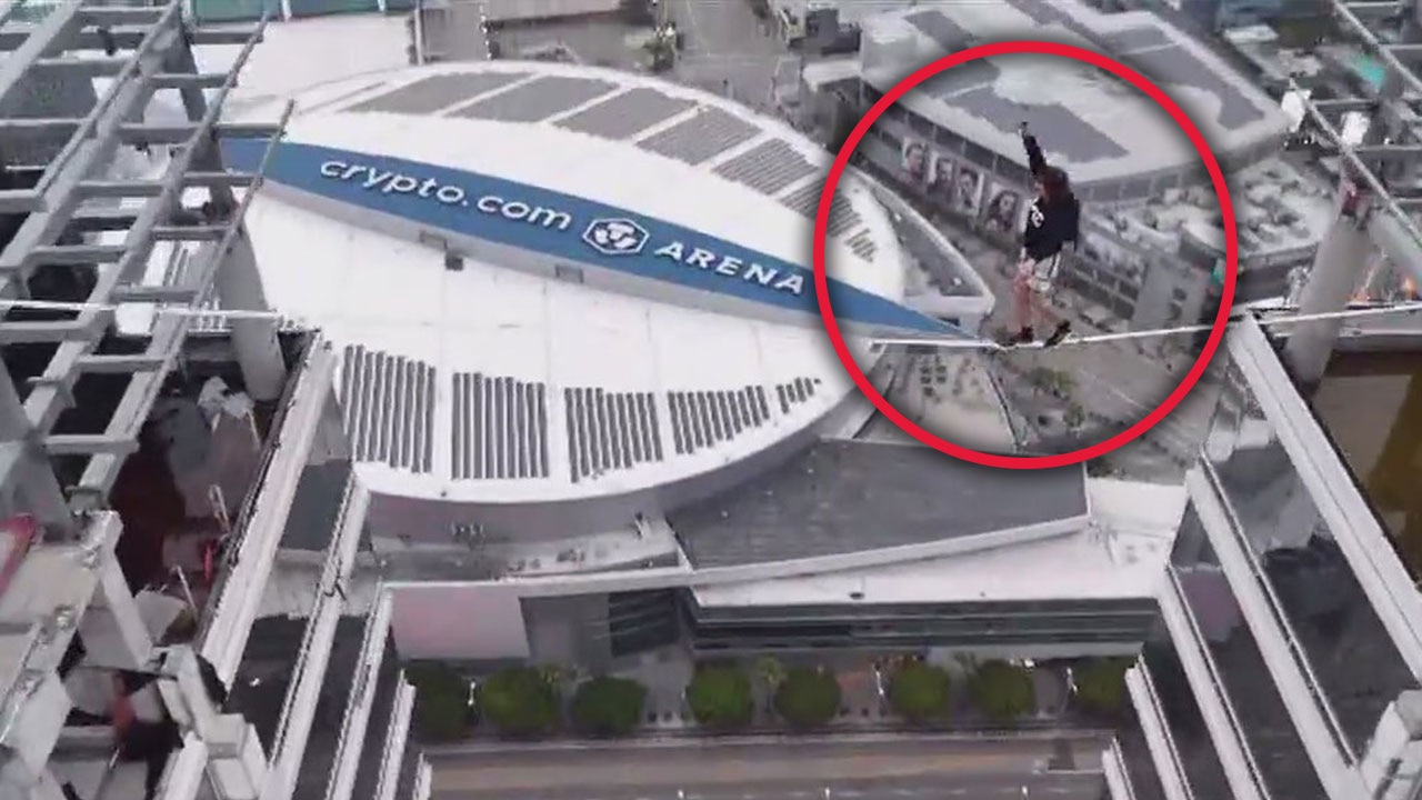 Man walks on slack line between 2 graffiti towers