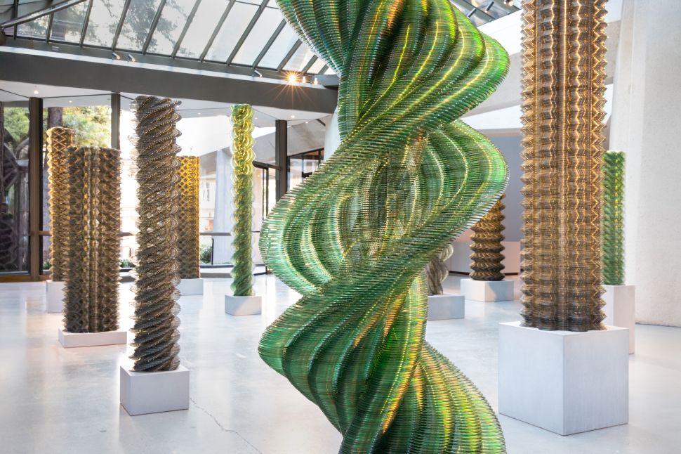 Installation view of Tara Donovan’s twisting column sculptures made of stacked translucent discs inside a light-filled modernist interior.
