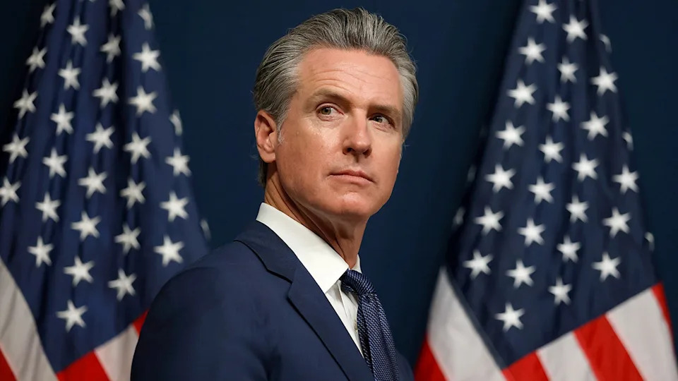 California Gov. Gavin Newsom with two American flags in the background.