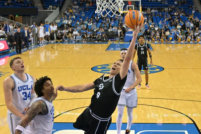 Dec 19, 2025; Los Angeles, California, USA; Cal Poly Mustangs guard Peter Bandelj (9) drives past UCLA Bruins guard Skyy Clark (55) for a basket during the second half at Pauley Pavilion presented by Wescom Financial.
