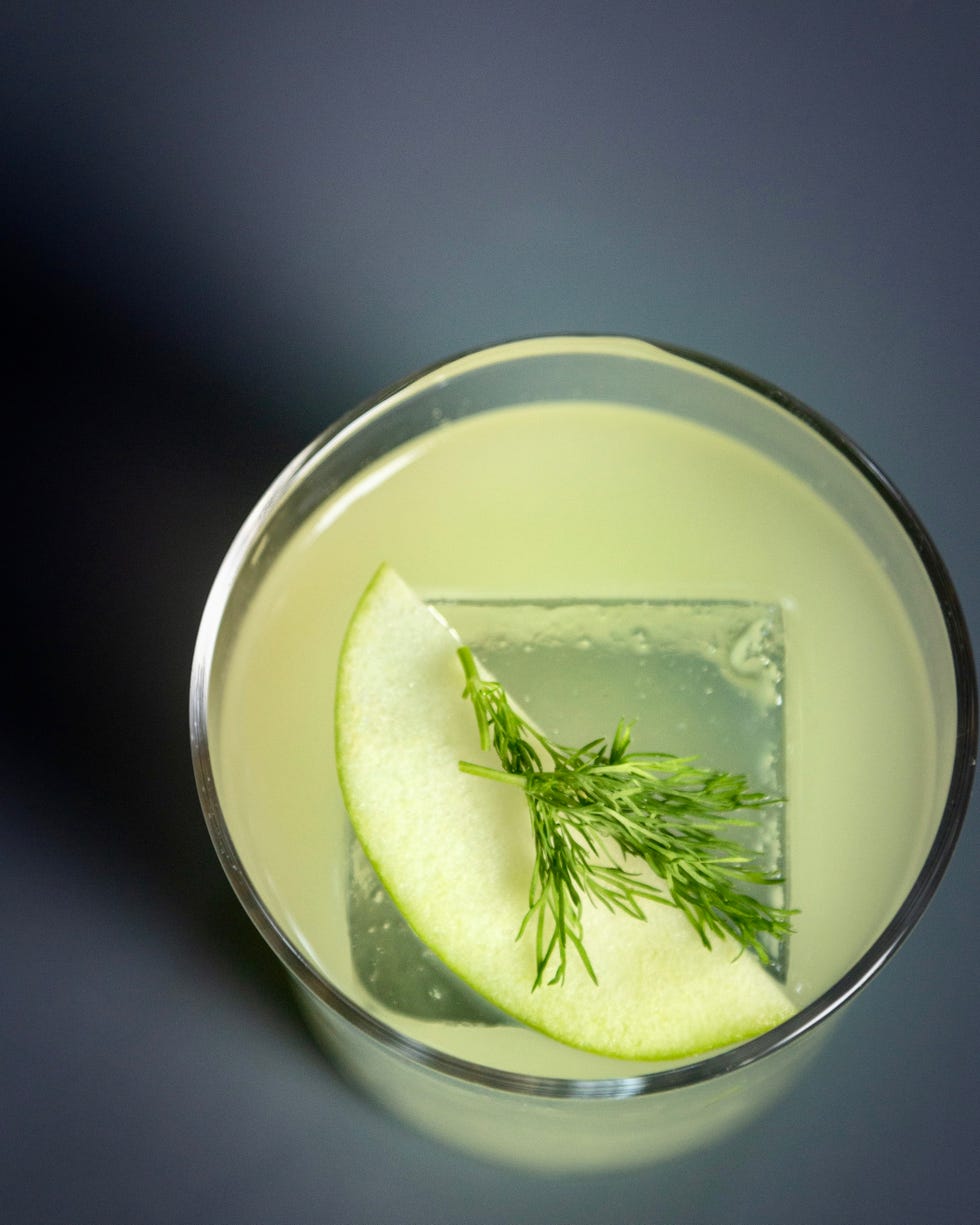 Cocktail with apple slice and dill garnish