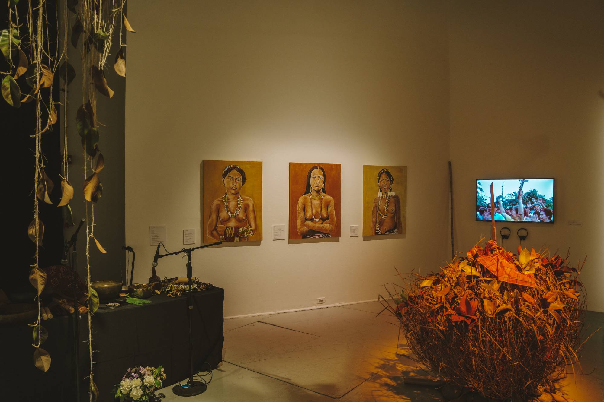 A broad view of multiple art pieces inside of a gallery with moody lighting. 