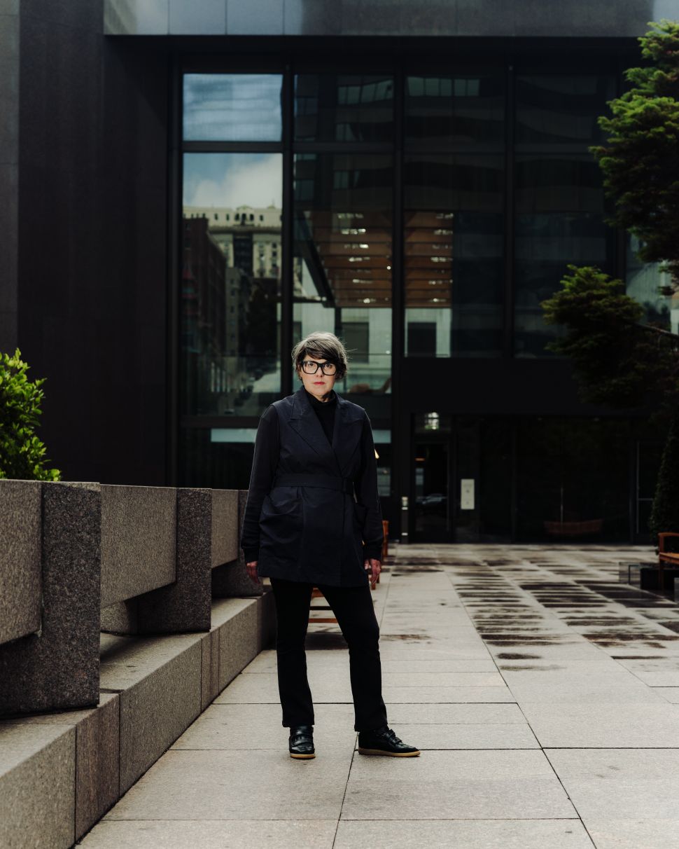 Portrait of Ali Gass standing outdoors near the Transamerica Pyramid, wearing dark clothing against a modern architectural backdrop.