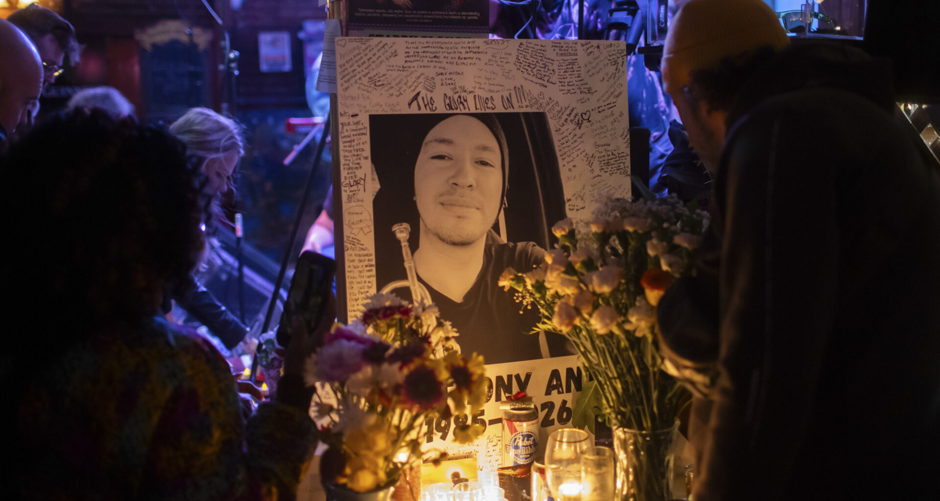 A photo of a man in a beanie is surrounded by candles