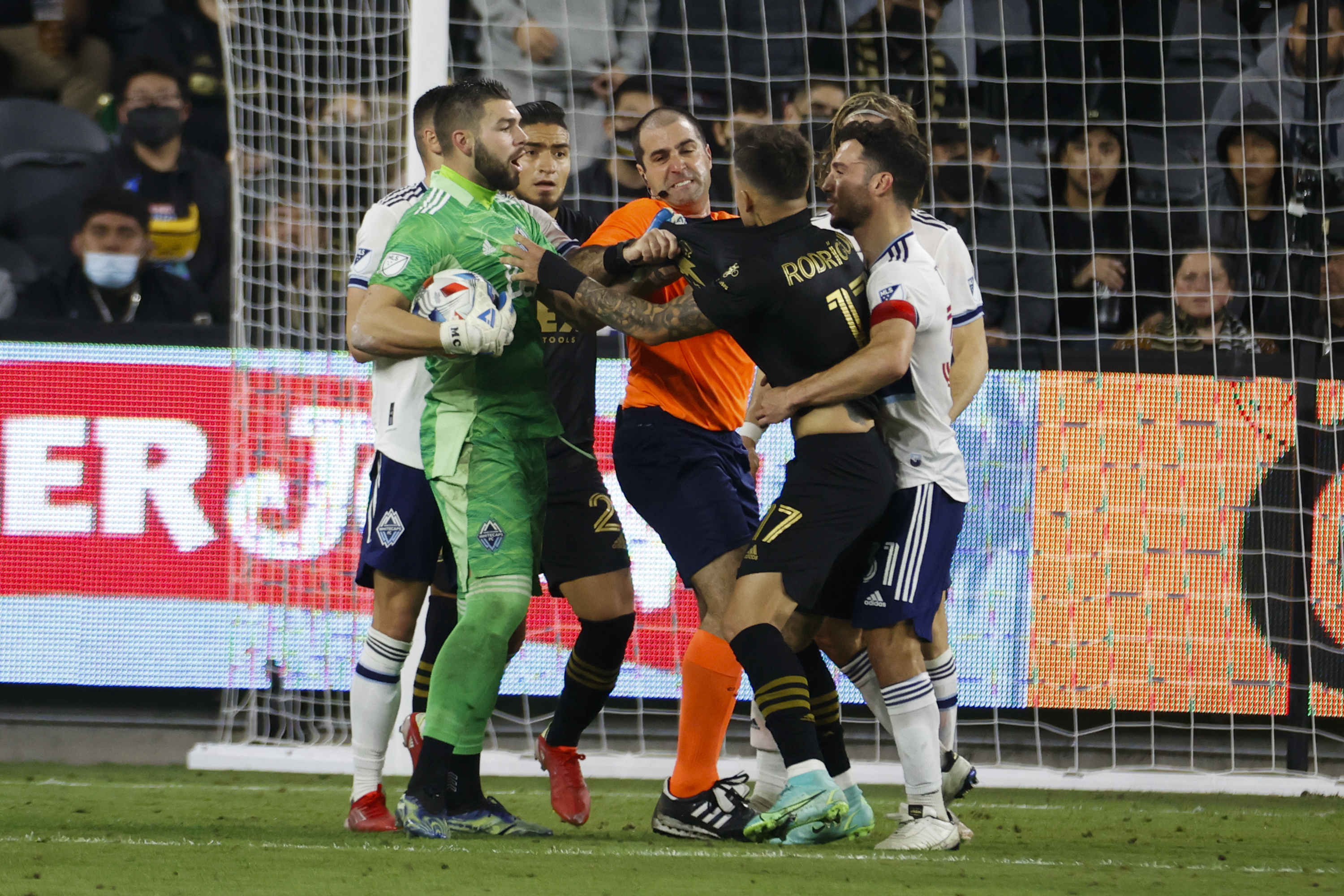 A referee and players try to separate LAFC forward Brian...