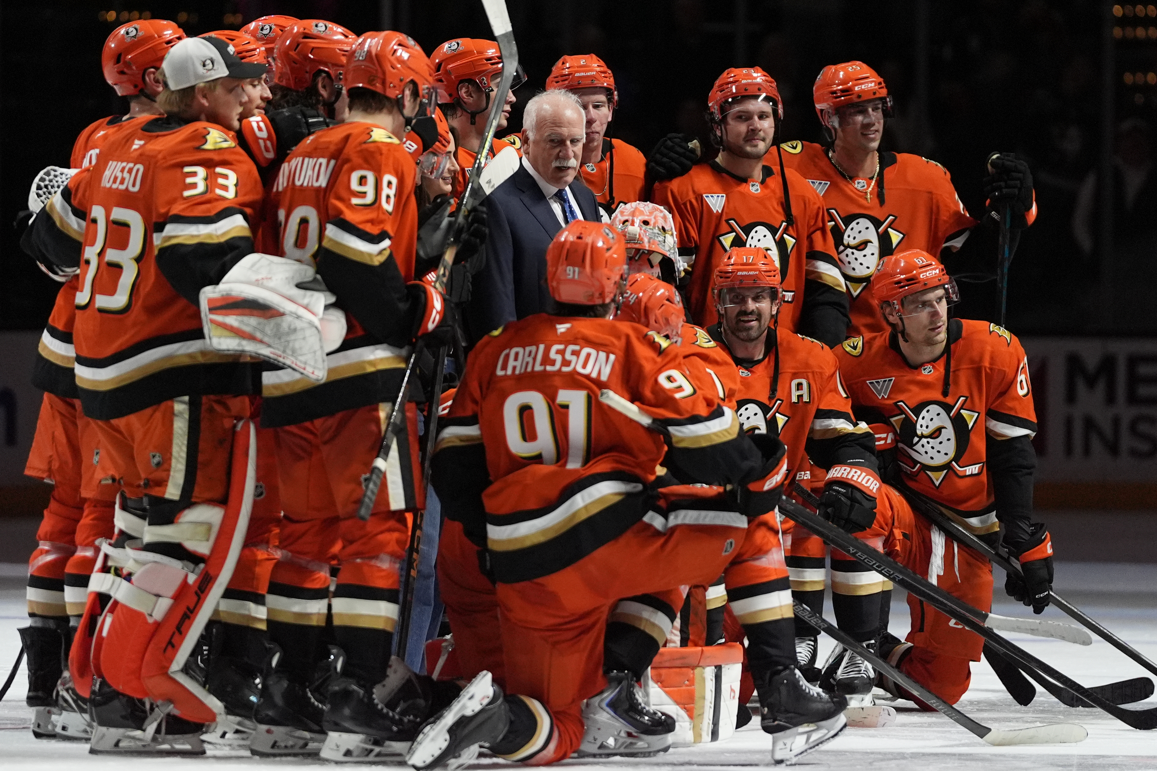 Ducks head coach Joel Quenneville, center, poses with players and...