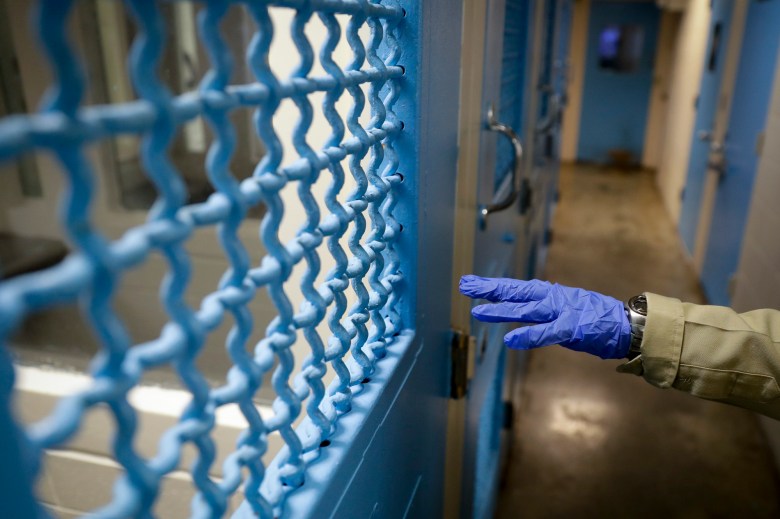 A gloved hand points to a holding cell at the hospital ward of the Twin Towers jail in Los Angeles on April 16, 2020. About 3,000 inmates were recently transferred out of jails to prisons, but on Thursday, the California Department of Corrections and Rehabilitation again suspended transfers following a rise in coronavirus cases. Photo by Chris Carlson, AP Photo