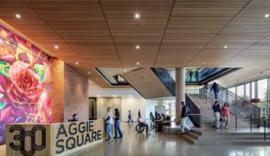 Bright modern lobby featuring a colorful mural, wooden accents, and people interacting.